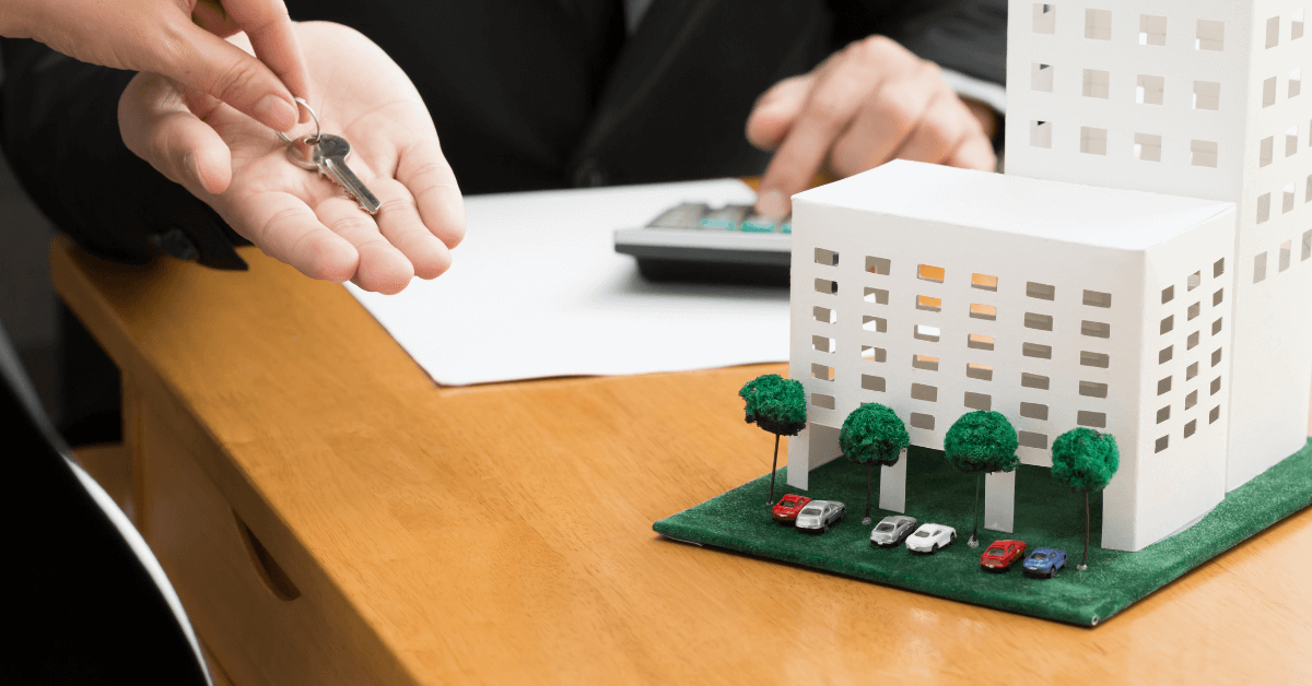 Signing a document with a miniature building representing condominium